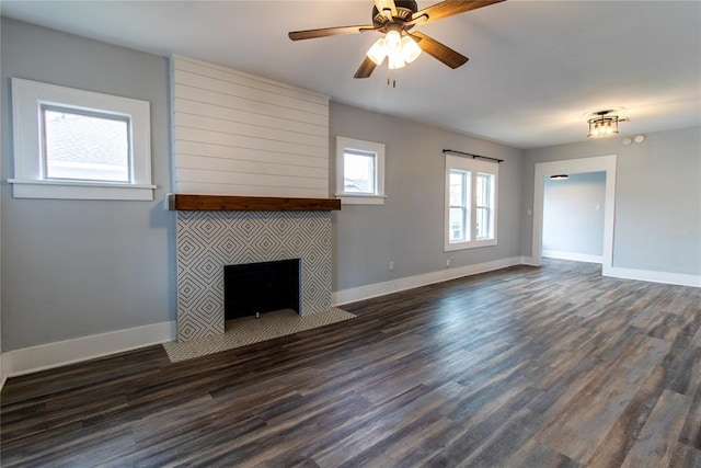 unfurnished living room featuring dark wood-type flooring, a fireplace, baseboards, and ceiling fan