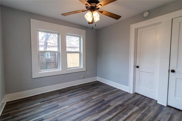 empty room with ceiling fan, baseboards, and dark wood finished floors