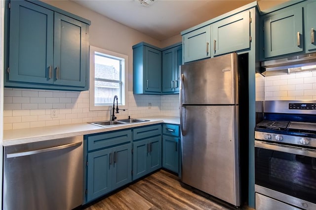 kitchen featuring stainless steel appliances, blue cabinets, a sink, and under cabinet range hood