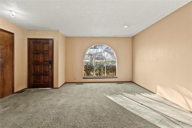 empty room with visible vents, a textured ceiling, and carpet