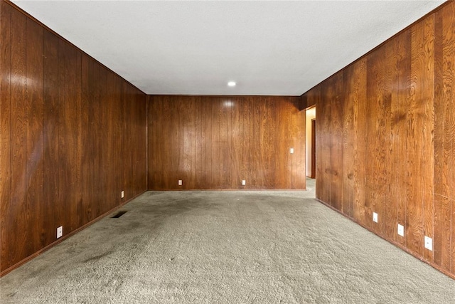 carpeted spare room with wooden walls