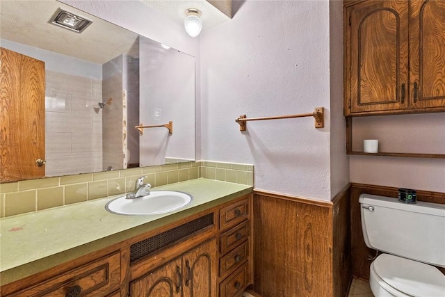 full bath with vanity, wooden walls, a wainscoted wall, walk in shower, and toilet