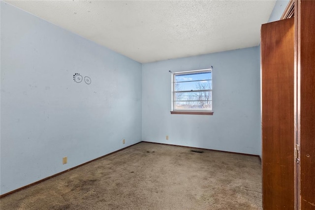 empty room with baseboards, visible vents, a textured ceiling, and carpet