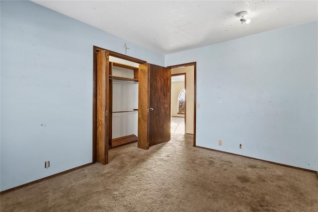 interior space featuring light colored carpet, baseboards, and a textured ceiling