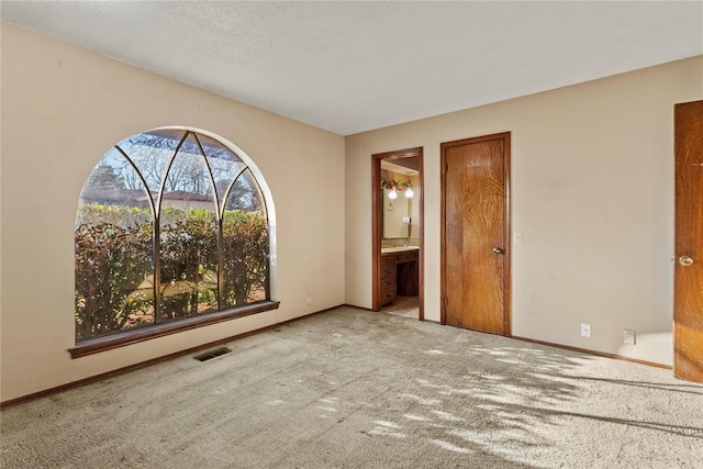 unfurnished bedroom with visible vents, baseboards, ensuite bath, and carpet flooring