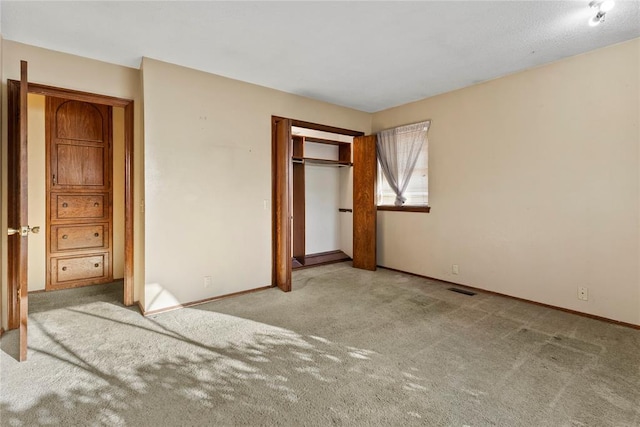 unfurnished bedroom featuring carpet, visible vents, a closet, and baseboards