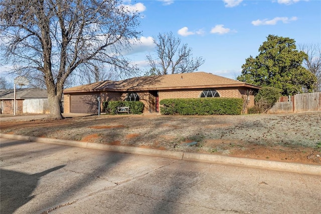 ranch-style house with brick siding, an attached garage, and fence