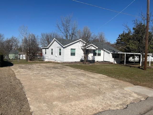 view of front of house with concrete driveway, a front lawn, and fence