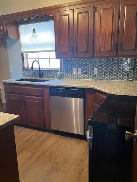 kitchen featuring light wood finished floors, tasteful backsplash, electric range, a sink, and dishwasher