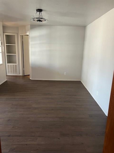 unfurnished room with dark wood-style floors, visible vents, and baseboards