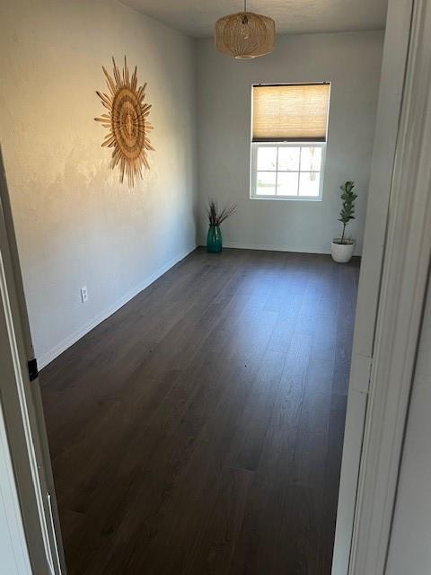 spare room with baseboards and dark wood finished floors