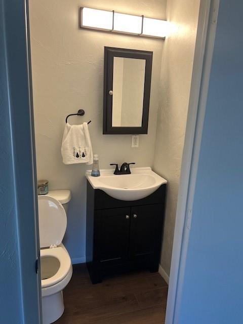 bathroom featuring toilet, wood finished floors, vanity, and baseboards