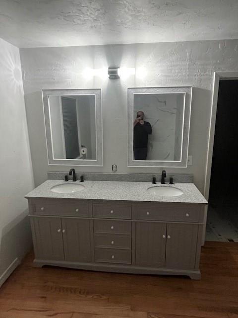 full bathroom featuring double vanity, a sink, and wood finished floors