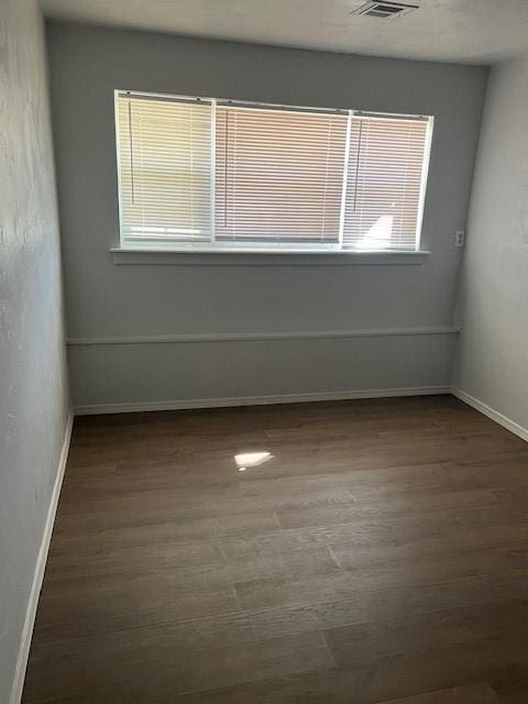 empty room with dark wood-style flooring and baseboards