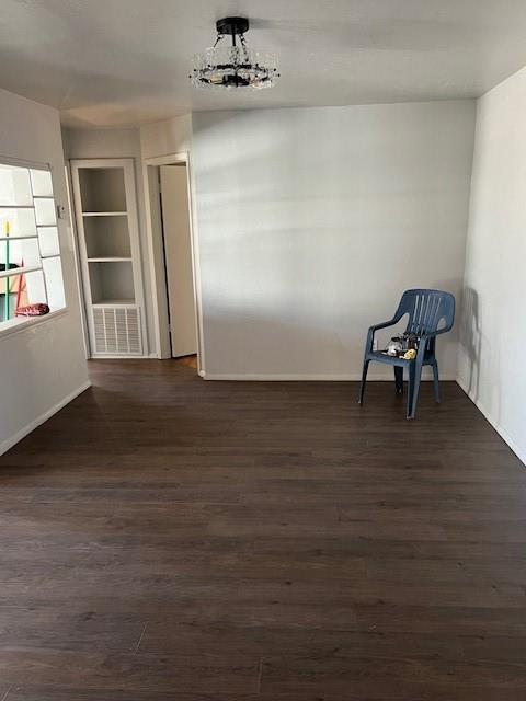 interior space with dark wood-style floors, baseboards, and an inviting chandelier