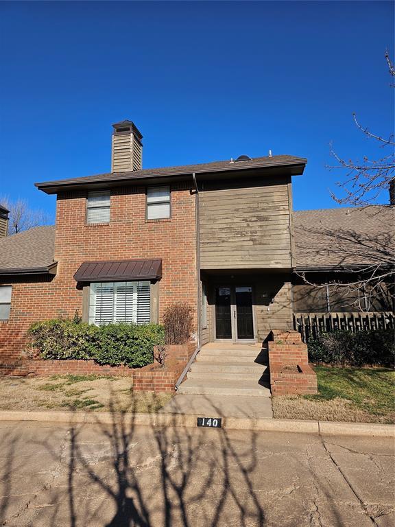 view of front of property with brick siding, french doors, and a chimney