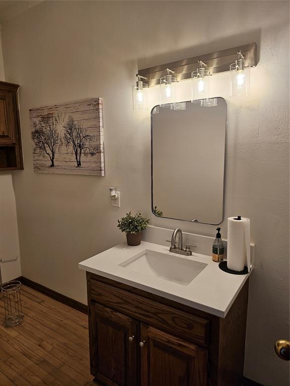 bathroom featuring baseboards, wood finished floors, and vanity