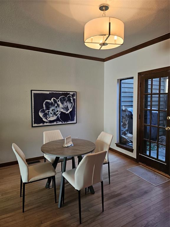 dining space with crown molding, wood finished floors, and baseboards