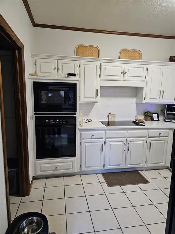 kitchen with white cabinets, black appliances, and light countertops