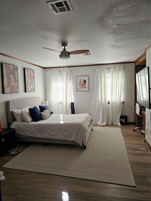 bedroom featuring multiple windows, wood finished floors, and visible vents