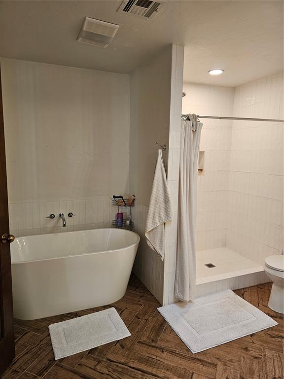 full bathroom with a soaking tub, visible vents, a stall shower, and toilet