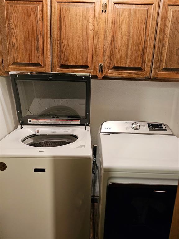 clothes washing area with cabinet space and independent washer and dryer