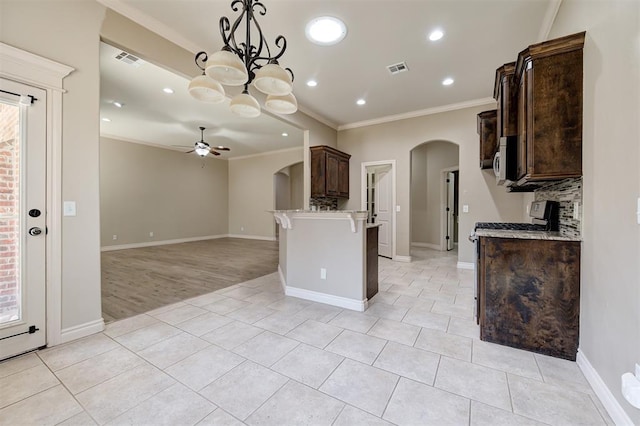 kitchen featuring dark brown cabinets, visible vents, arched walkways, and ornamental molding