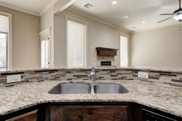 kitchen featuring visible vents, a sink, black dishwasher, a fireplace, and crown molding