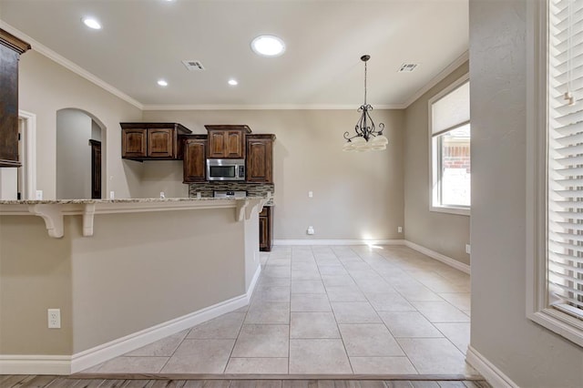 kitchen featuring stainless steel microwave, a breakfast bar area, and visible vents