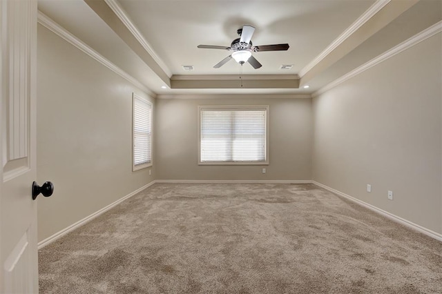 unfurnished room with a tray ceiling, crown molding, carpet, and visible vents