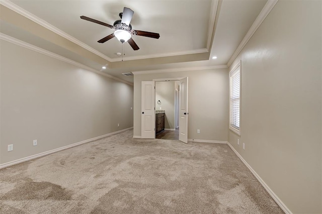 unfurnished bedroom featuring a tray ceiling, baseboards, carpet, and ornamental molding