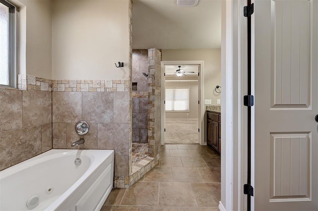 bathroom featuring tile walls, a stall shower, tile patterned floors, a tub with jets, and vanity