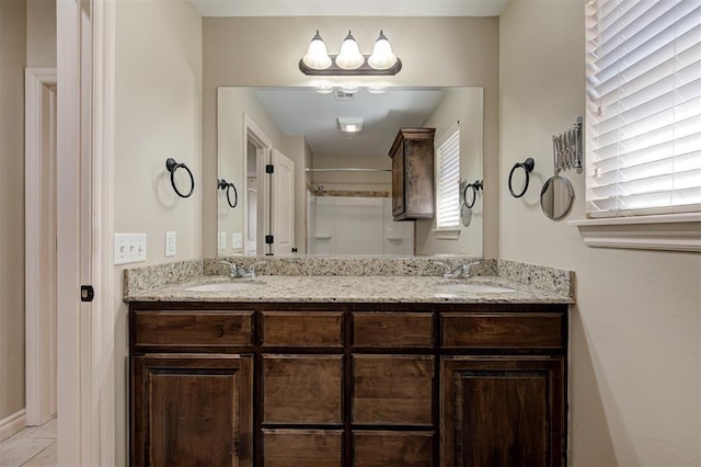 full bath featuring double vanity, visible vents, walk in shower, and a sink