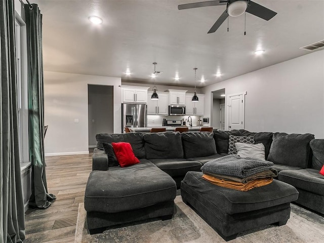 living area featuring recessed lighting, visible vents, light wood-style flooring, a ceiling fan, and baseboards