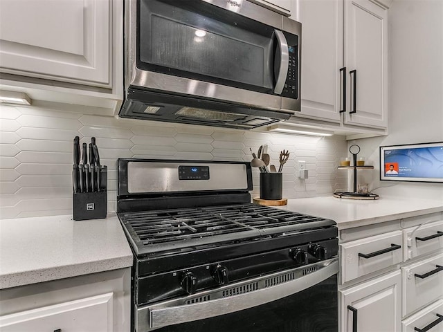 kitchen with appliances with stainless steel finishes, white cabinets, and backsplash