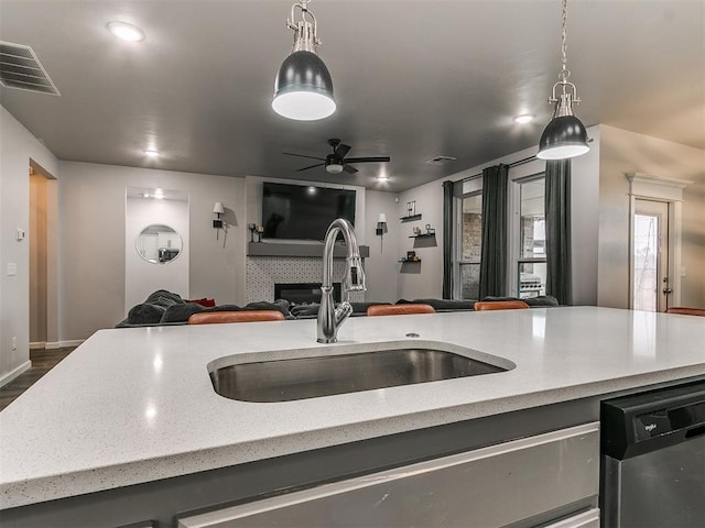 kitchen with visible vents, dishwasher, open floor plan, a fireplace, and a sink