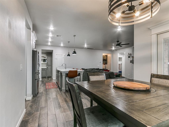 dining room featuring ceiling fan, visible vents, baseboards, wood tiled floor, and a raised ceiling