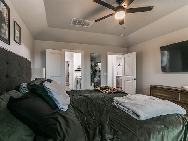 bedroom with a tray ceiling, visible vents, connected bathroom, vaulted ceiling, and ceiling fan