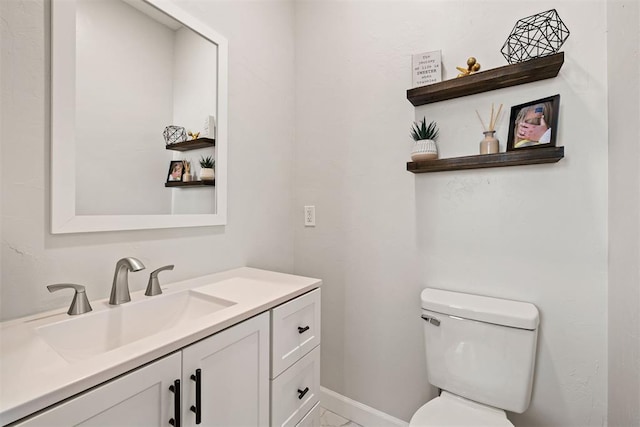 bathroom featuring baseboards, vanity, and toilet