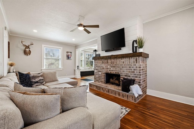 living area with ornamental molding, a fireplace, wood finished floors, and baseboards