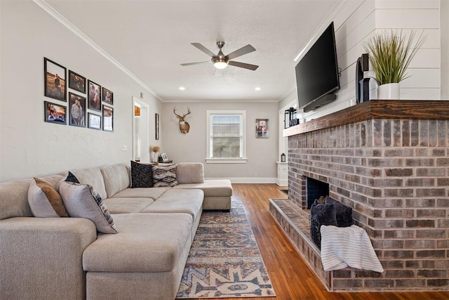 living area featuring a fireplace, wood finished floors, a ceiling fan, baseboards, and ornamental molding