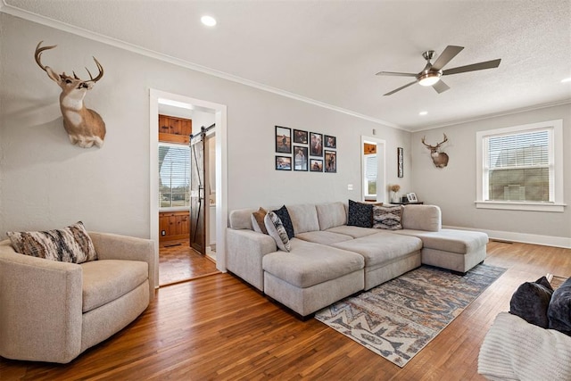 living room with a healthy amount of sunlight, a barn door, and wood finished floors