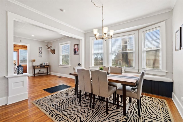 dining room featuring baseboards, ornamental molding, light wood-type flooring, and an inviting chandelier