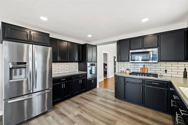 kitchen featuring appliances with stainless steel finishes, light wood-type flooring, light countertops, and dark cabinetry