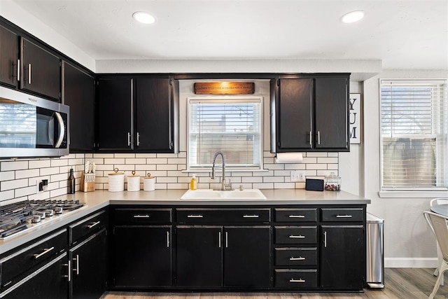 kitchen featuring tasteful backsplash, stainless steel appliances, a sink, and light countertops