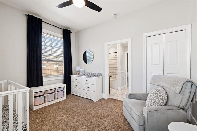 bedroom featuring light carpet, a closet, ensuite bath, and a ceiling fan