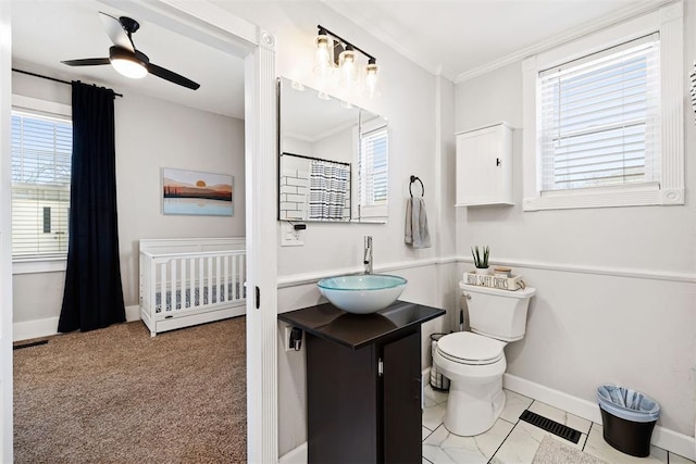 bathroom featuring toilet, vanity, baseboards, visible vents, and crown molding