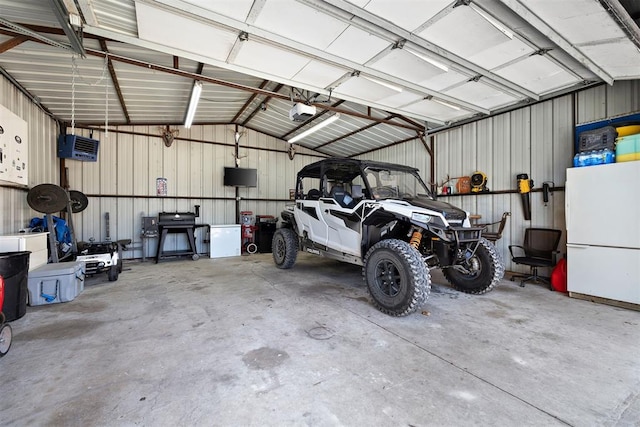 garage featuring a garage door opener, freestanding refrigerator, and metal wall