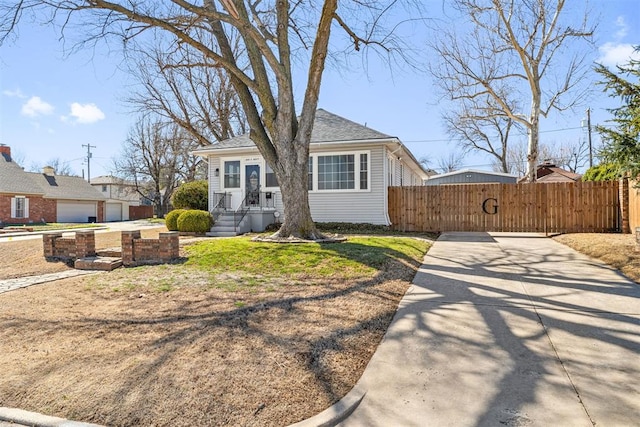 bungalow-style home with concrete driveway, roof with shingles, and fence