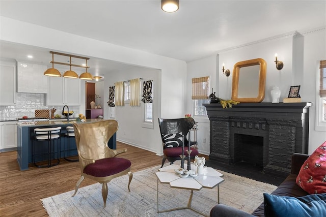 living room featuring a fireplace, baseboards, and wood finished floors